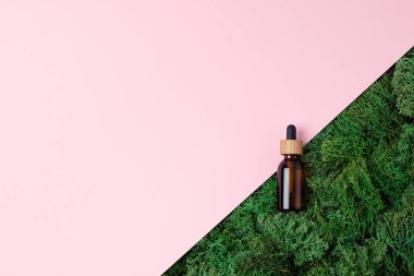 Pembe arka planda yosun olan kozmetik şişesi. Düz yat, boşluğu kopyala.