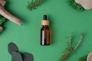 Yeşil arka planda ahşap ve yosun bulunan kozmetik şişesi. Düz yatıyordu.