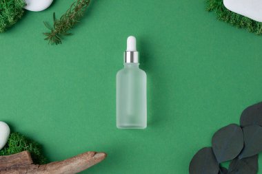 Yeşil arka planda ahşap ve yosun bulunan kozmetik şişesi. Düz yatıyordu.