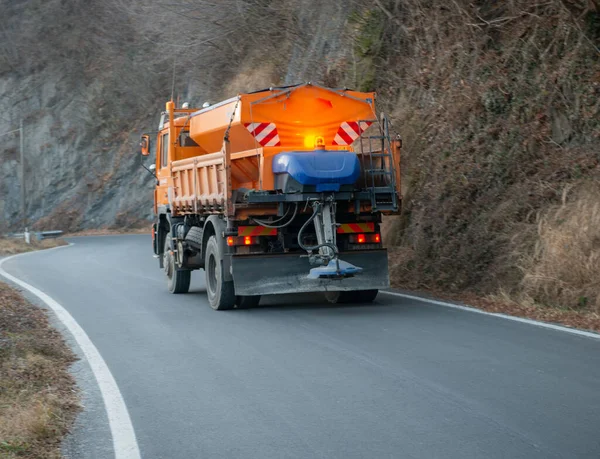 Salt-spreading vehicle on a winding road