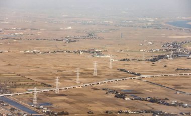 Altın kahverengi tarım arazisi ve sise rağmen elektrik kuleleri hattı