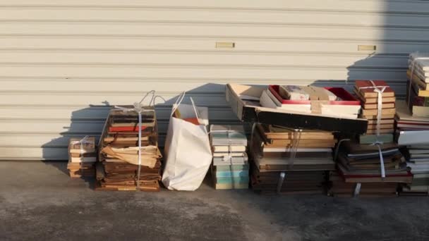 Massevis av gamle bøker samlet på gaten for resirkulering i sol og skygge – stockvideo