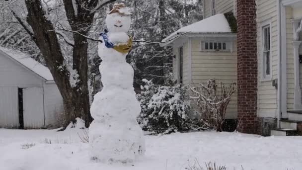 Ön bahçede kar yağışı yavaş olan dev bir kardan adam. — Stok video