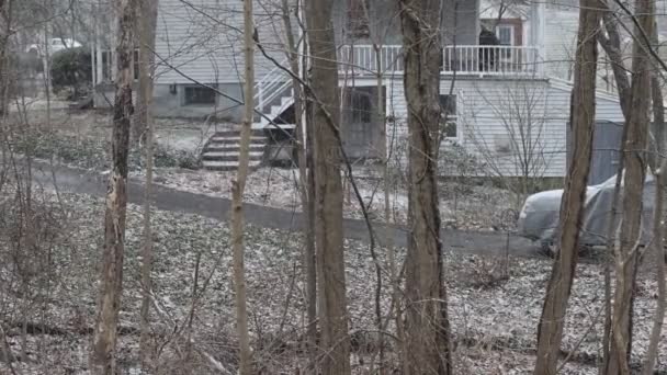 La neige tombe lentement devant la maison et la voiture couverte en hiver — Video