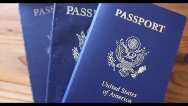 Sartén lenta a través de la pila de tres pasaporte de EE.UU. en la mesa de grano de madera — Vídeo de stock