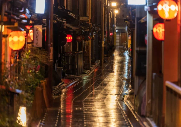 Linha de lanternas vermelhas beco molhado em Kyoto à noite — Fotografia de Stock