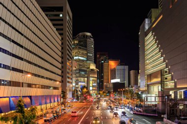 Gece şehir merkezinde trafik ışığı olan geniş bir yol.