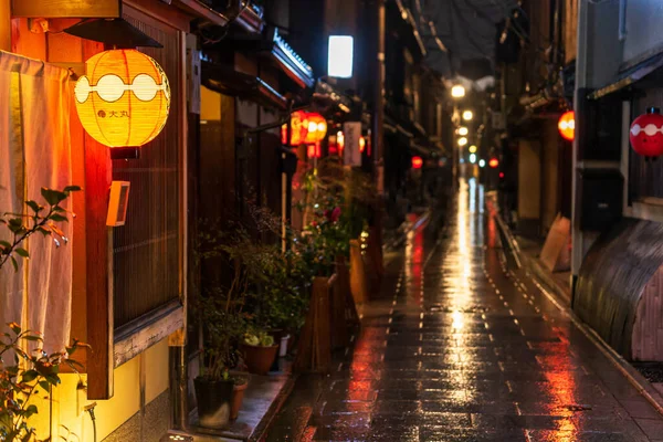 Kırmızı fener yağmurdan sonra karanlık Japon caddesinde girişi aydınlatıyor
