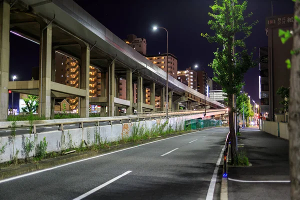 Töm gata och förhöjd vägbana genom stadsområde på natten — Stockfoto