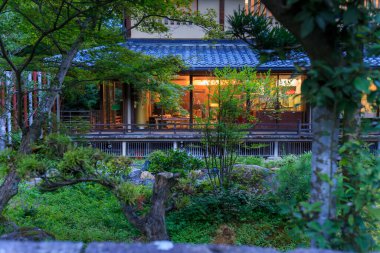 Alacakaranlıkta yanan restoranın etrafındaki Japon bahçesi