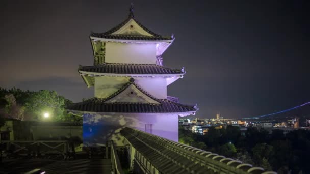 Pan sobre castillo mirador hacia puente colgante y pequeño centro de la ciudad por la noche — Vídeos de Stock