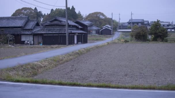 Cars zip by Japanese country road through small farms a dusk — Vídeo de Stock
