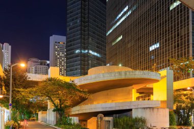 Yüksek binalar gece şehir merkezindeki otoparkın etrafını sarmış.