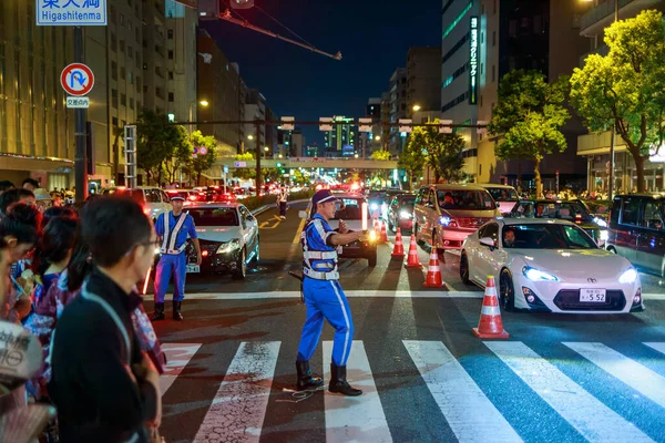 Osaka, Japón - 25 de julio de 2015: Oficial de control de tráfico dirige a los peatones a través de la intersección después del festival de verano Tenjin Matsuri — Foto de Stock