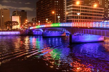 Gece şehir merkezinde nehir üzerinde renkli bir köprü.