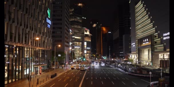 Osaka, Japan: May 1, 2022: Cars start driving as light changes on main road in front of JR Osaka Station at night — стокове відео