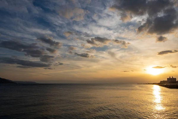 Sunset reflects in calm ocean water as clouds pass overhead — Fotografia de Stock