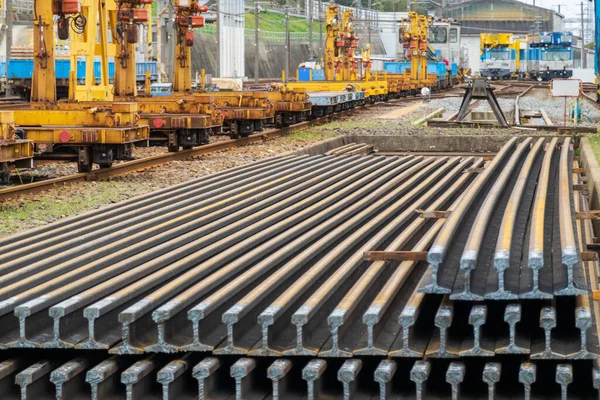 Lengths of rail stacked in train yard — стоковое фото