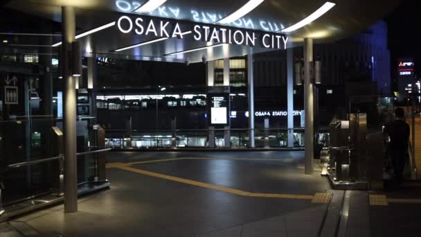 Osaka, Japan - April 1, 2022: Slow pan over entrance to Osaka Station City as train departs in background at night — 비디오