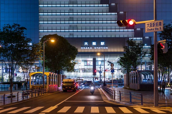 Osaka, Japan - May 1, 2022: Single motorbike approaches traffic light in front of JR Osaka Station at night — Stock Photo, Image