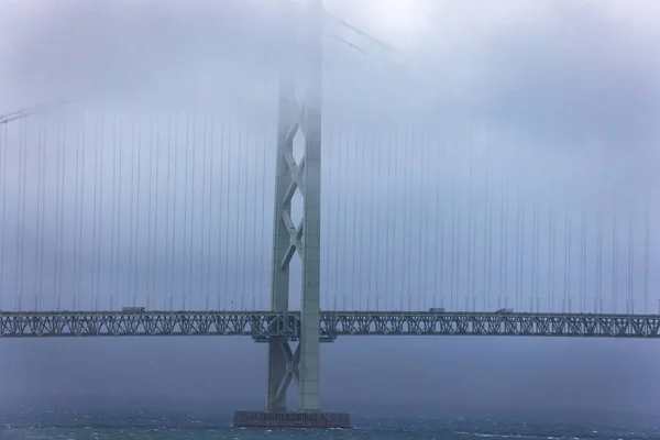 Suspension bridge tower in clouds and fog on grey stormy day — Stockfoto