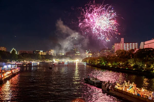 Yaz festivalinde nehir kenarında mor havai fişekler patlıyor.