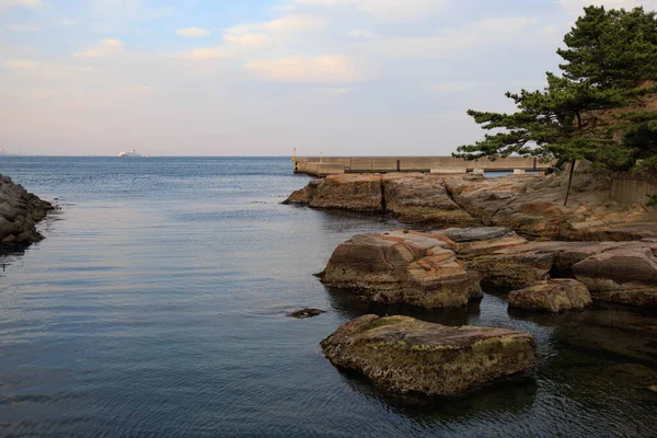 Su kanalının yanında gün batımından önceki bulutların olduğu eşsiz yıpranmış kayalar.