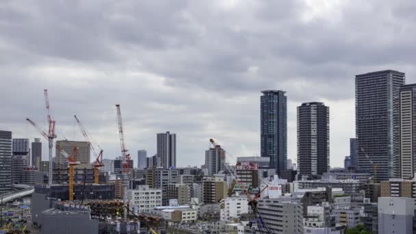 Осака, Япония - 12 мая 2022 года: Строительные краны работают над строительством линии горизонта города, когда облака движутся над головой, с течением времени — стоковое видео