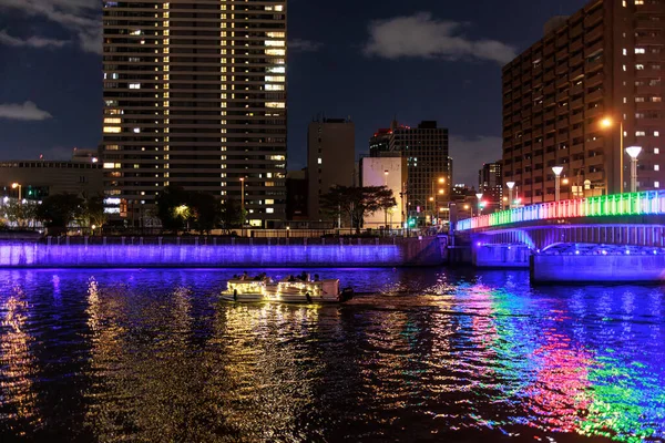 Renkli köprü gece boyunca nehirde dalgalanmaları yansıtır.