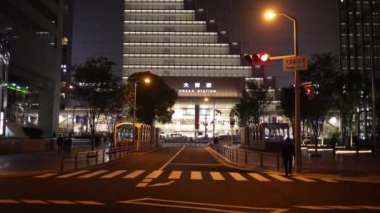 Osaka, Japonya - 1 Mayıs 2022: JR Osaka İstasyonu 'nun önünde gece yavaşça ilerleyen araçlarla sessiz kavşak