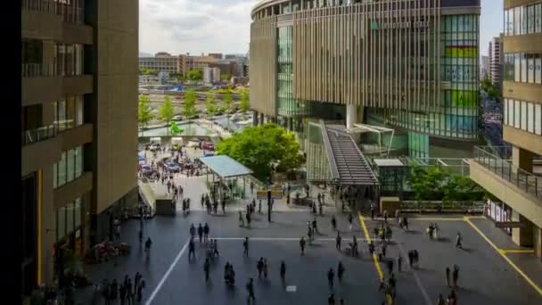 Осака, Япония - 12 мая 2022 года: Толпы людей проходят через оживленную площадь между вокзалом Осака и Гранд Фронтом в пасмурный день — стоковое видео