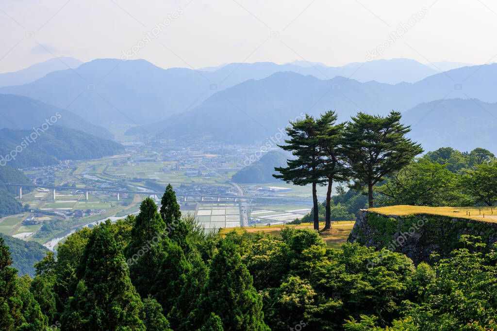 Trees atop ancient stone walls overlooking rural town in mountains. High quality photo