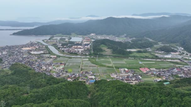 山や霧を背景に小さな沿岸の町や田んぼ 高品質4K映像 — ストック動画