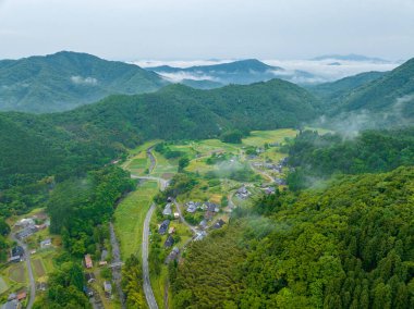 Sabahın erken saatlerinde kırsal dağ köyündeki küçük çiftliklerin üzerinden sis geçiyor. Yüksek kalite fotoğraf