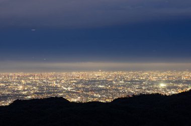 Geceleri geniş şehre tepeden bakan karanlık dağ. Yüksek kalite fotoğraf