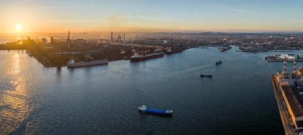 Panorama: Aerial view of ships docked and anchored at industrial harbor as sun sets. High quality photo