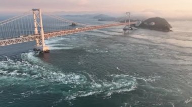 Gün batımında Naruto asma köprüsünün altındaki girdaplarda geri çekiliyoruz. Yüksek kalite 4k görüntü
