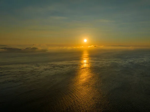 Alçak güneş bulutların arasından parlar ve şafak vakti açık okyanusta yansıtır. Yüksek kalite fotoğraf