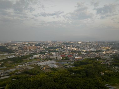 Alacakaranlıkta yeşil tepelerin kenarındaki genişleyen şehrin hava manzarası. Yüksek kalite fotoğraf