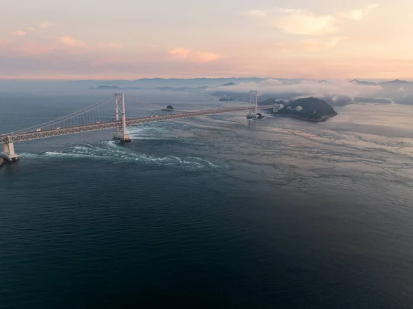 Strong tidal current flows under Naruto suspension bridge at sunset. High quality photo