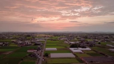 Descending to rural farmland with dramatic pink sunset. High quality 4k footage