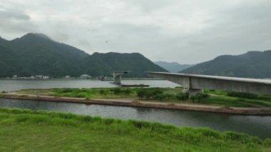 Slow move towards bridge under construction over wide river near mountains. High quality 4k footage