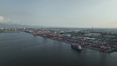 Container ship maneuvers into docking position under loading cranes on pier. High quality 4k footage