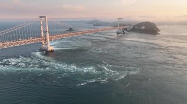 Aerial: Move in towards whirlpools and suspension bridge at sunset. High quality 4k footage