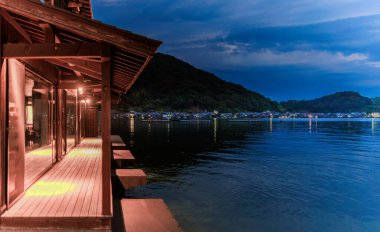 Kyoto 'nun küçük balıkçı kasabası Ine' de gece çökerken su kenarındaki ahşap güverte. Yüksek kalite fotoğraf