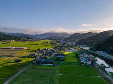 Sabahın erken saatlerinde küçük bir köyde ve pirinç tarlalarında güneş dağların arasından doğar. Yüksek kalite fotoğraf