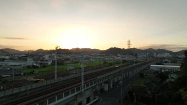 Küçük kasaba ve dağların yanındaki yüksek demiryolu rayları üzerinde parlak gün doğumu. Yüksek kalite 4k görüntü