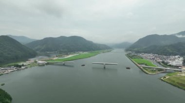 Aerial swoop into unfinished bridge span and small town amid mountain landscape. High quality 4k footage