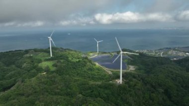 Aerial view of wind turbines and solar panels at green energy farm on coast. High quality 4k footage