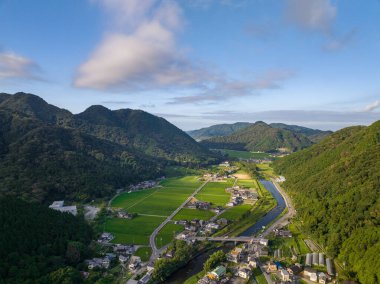 Morning sun hits rice fields and small farming community along river in valley. High quality photo